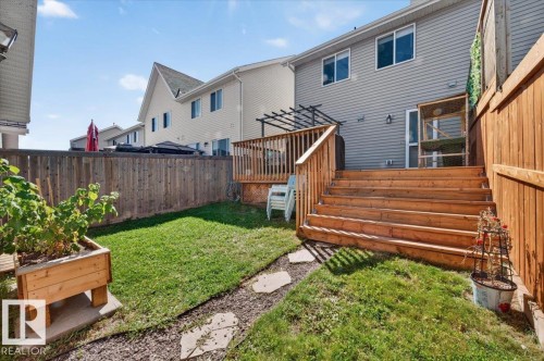 Wooden privacy fencing enclosing a green lawn, multi-level wood deck with pergola, and wooden raised planter box - 1217 76 Street Sw, Edmonton, AB 