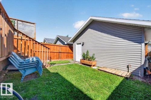 Manicured lawn with a wood fence, wooden deck and stairs, and a detached building with horizontal siding - 1217 76 Street Sw, Edmonton, AB 