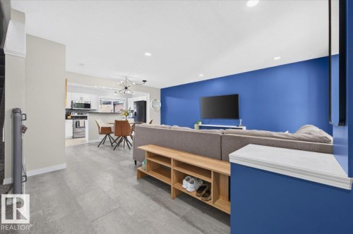Open-concept living space with recessed lighting, light-toned flooring, and a modern kitchen featuring white cabinetry and stainless steel appliances - 1217 76 Street Sw, Edmonton, AB 