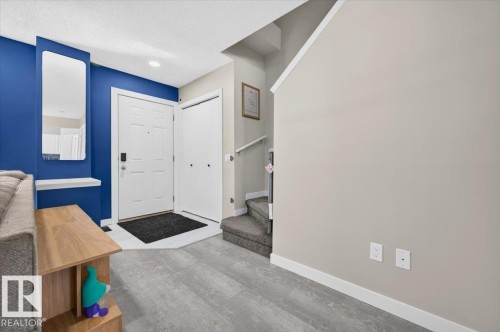 Entryway with a white paneled door, wood-finish flooring, and a mirrored wall accent - 1217 76 Street Sw, Edmonton, AB 
