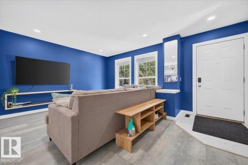 Recessed ceiling lighting, wood-finish flooring, white trim windows, and a white panel door with modern hardware - 1217 76 Street Sw, Edmonton, AB 