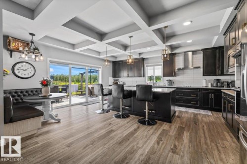 Expansive kitchen featuring wood-finish flooring, dark cabinetry, and a large center island with counter seating - 5203 23A Avenue Sw, Edmonton, AB - Indoor