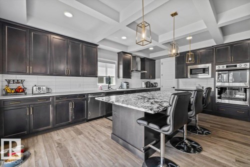 Kitchen featuring dark wood-finish cabinetry, white subway tile backsplash, white countertops, and wood-finish flooring - 5203 23A Avenue Sw, Edmonton, AB - Indoor Photo Showing Kitchen With Upgraded Kitchen