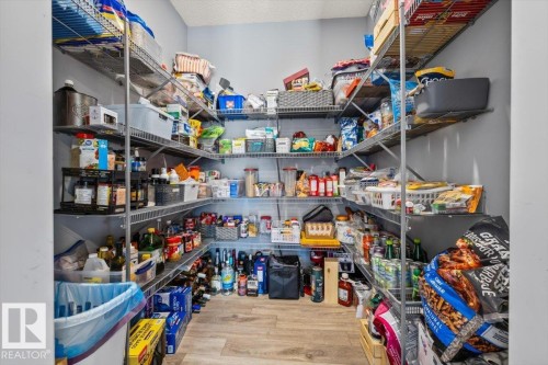Spacious pantry featuring extensive wire shelving, light wood-finish flooring, and light gray walls - 5203 23A Avenue Sw, Edmonton, AB - Indoor With Storage