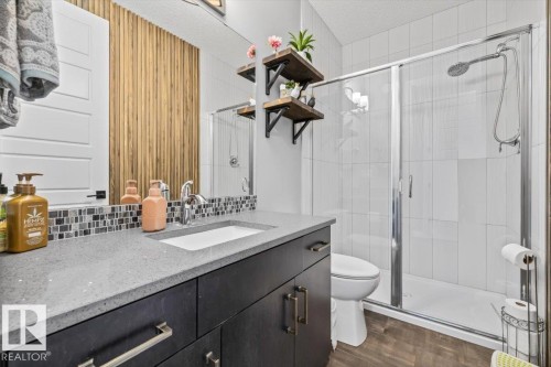 Bathroom featuring a dark wood-finish vanity with a light speckled countertop, an undermount sink, and a chrome faucet - 5203 23A Avenue Sw, Edmonton, AB - Indoor Photo Showing Bathroom