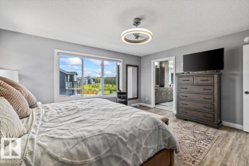 Bedroom featuring large window, wood-finish flooring, and a contemporary ceiling light fixture - 5203 23A Avenue Sw, Edmonton, AB - Indoor Photo Showing Bedroom