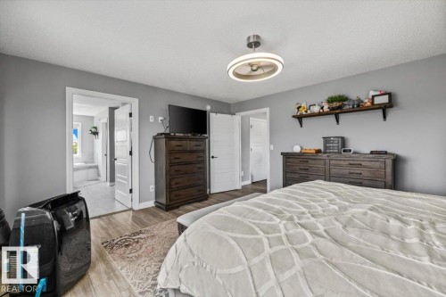 Spacious room featuring light gray walls, wood-finish flooring, and a modern ceiling light fixture - 5203 23A Avenue Sw, Edmonton, AB - Indoor Photo Showing Bedroom