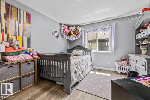 Well-lit room featuring wood-finish flooring, a white-framed window, and light grey wall paint - 5203 23A Avenue Sw, Edmonton, AB - Indoor Photo Showing Bedroom