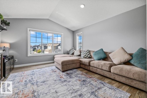 Living area featuring a vaulted ceiling with recessed lighting, large window, and wood-finish flooring - 5203 23A Avenue Sw, Edmonton, AB - Indoor Photo Showing Living Room
