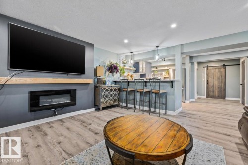 Entertainment wall with a mounted media console and built-in electric fireplace - 5203 23A Avenue Sw, Edmonton, AB - Indoor Photo Showing Living Room With Fireplace