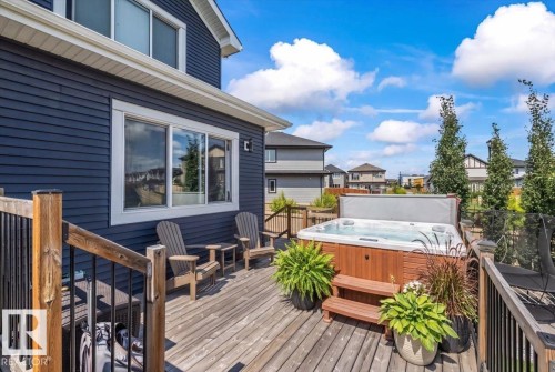 Expansive outdoor deck featuring a built-in hot tub, durable wood decking, and dark siding exterior - 5203 23A Avenue Sw, Edmonton, AB - Outdoor With Deck Patio Veranda With Exterior