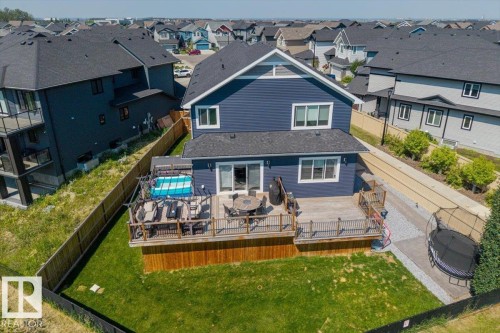 Rear exterior featuring a spacious elevated deck with wood railings, leading to a private fenced yard with a manicured lawn - 5203 23A Avenue Sw, Edmonton, AB - Outdoor With Deck Patio Veranda