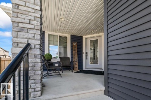 Exterior featuring a covered porch with a stone column and dark siding - 5203 23A Avenue Sw, Edmonton, AB - Outdoor