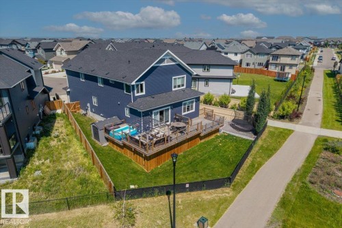 Blue exterior residence with a spacious wooden deck, fenced yard, and direct access to a paved pathway - 5203 23A Avenue Sw, Edmonton, AB - Outdoor With View