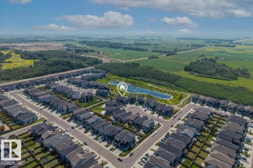 Aerial perspective of a developed residential area featuring a central pond with walking paths - 5203 23A Avenue Sw, Edmonton, AB - Outdoor With View