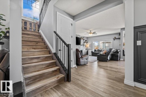 Open-concept living area with wood-finish flooring, a contemporary fireplace, and a large window overlooking the outdoor area - 5203 23A Avenue Sw, Edmonton, AB - Indoor Photo Showing Other Room