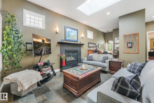 Recessed lighting, skylight, slate tile flooring, wall sconces, and a gas fireplace with a dark tile surround - 10531 137 Street Nw, Edmonton, AB 