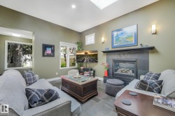 Living area featuring a fireplace with a stone surround, a skylight, recessed lighting, and wall sconces - 