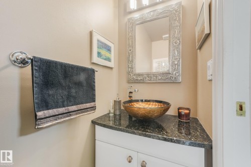 Vanity with dark speckled countertop, decorative vessel sink, wall-mounted mirror, and chrome towel bar - 10531 137 Street Nw, Edmonton, AB 