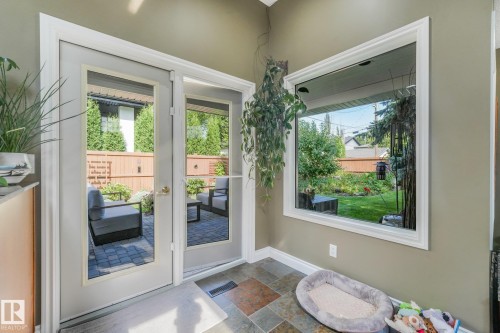 French doors opening to a paver patio, a fenced yard with mature trees, and multi-tone tile flooring - 10531 137 Street Nw, Edmonton, AB 