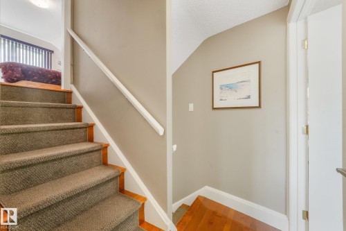 Staircase featuring wood treads with carpet runners, white handrail, and neutral wall paint - 10531 137 Street Nw, Edmonton, AB 