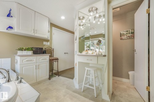White cabinetry with recessed panel doors, built-in vanity with mirror and task lighting, recessed overhead lighting, and a built-in soaker tub - 10531 137 Street Nw, Edmonton, AB 
