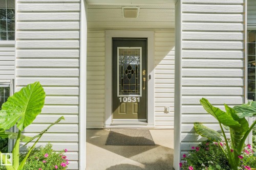 Covered entry with concrete flooring, decorative glass front door, and white siding exterior - 10531 137 Street Nw, Edmonton, AB 