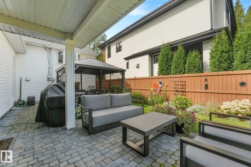 Paved patio area, covered outdoor space, a gazebo,  landscaped garden beds, and a wood fence with planted evergreens - 10531 137 Street Nw, Edmonton, AB 