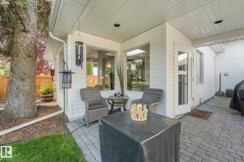 Outdoor covered patio featuring paver flooring, white siding, and a wooden fence - 10531 137 Street Nw, Edmonton, AB 