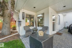 Outdoor covered patio featuring paver flooring, white siding, and a wooden fence - 