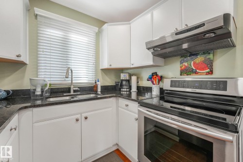 Kitchen featuring white cabinetry, granite countertops, a stainless steel sink with a gooseneck faucet, and stainless steel appliances - 10531 137 Street Nw, Edmonton, AB 