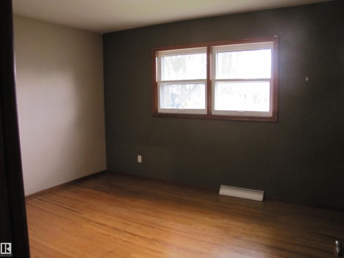 Hardwood-style flooring throughout with baseboard heating and a multi-pane window - 9512 63 Avenue Nw, Edmonton, AB 