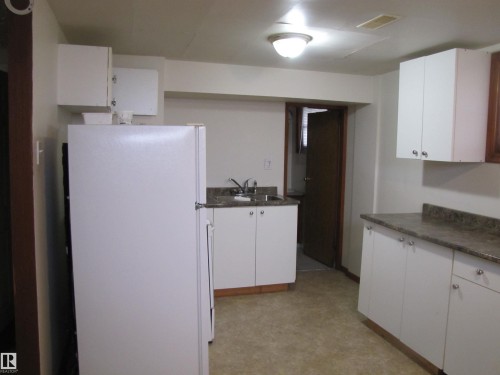 White cabinetry with brushed nickel hardware, laminate countertops, and vinyl flooring - 9512 63 Avenue Nw, Edmonton, AB 