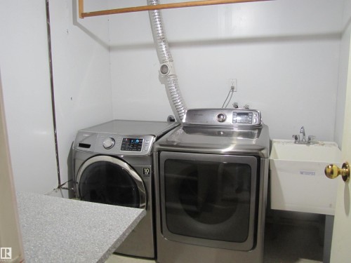 Laundry area featuring a utility sink, a wall-mounted wooden hanging rod, and a speckled countertop - 9512 63 Avenue Nw, Edmonton, AB 