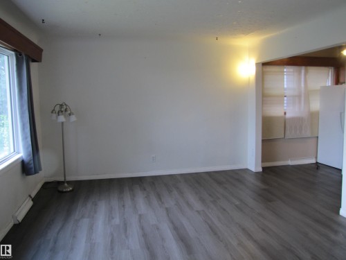 Wood-finish flooring throughout, white painted walls, and a large window with a wood cornice - 9512 63 Avenue Nw, Edmonton, AB 
