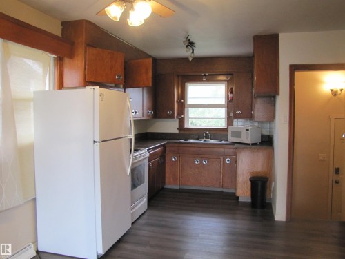 Wood-finish flooring with perimeter cabinetry, countertop space, and a built-in sink - 9512 63 Avenue Nw, Edmonton, AB 
