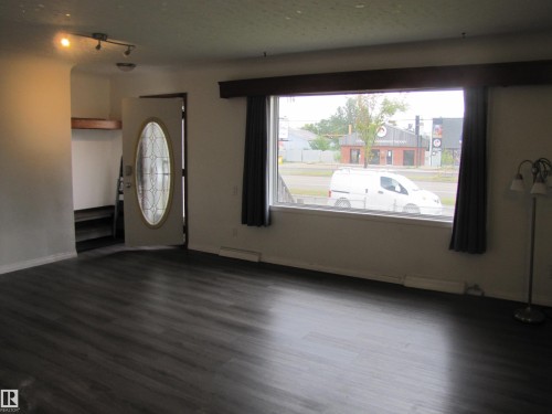 Dark wood-finish flooring throughout, bright entryway with a decorative glass-insert door, and a wide picture window - 9512 63 Avenue Nw, Edmonton, AB 