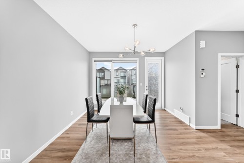 Wood-finish flooring, contemporary chandelier, sliding glass door, and white paneled door - 479 39 St Sw, Edmonton, AB 