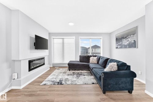Spacious living area featuring wood-finish flooring, an electric fireplace, a recessed ceiling light, and white trim - 479 39 St Sw, Edmonton, AB 
