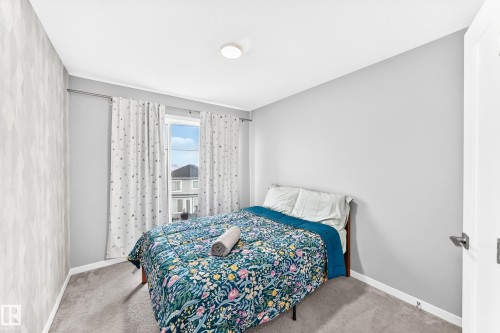 Carpeted flooring, window with drapes, flush mount ceiling light, and textured accent wall - 479 39 St Sw, Edmonton, AB 