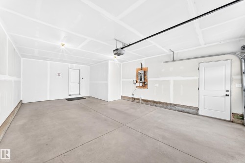 Spacious garage with exposed ceiling joists, concrete flooring, and two panel doors - 479 39 St Sw, Edmonton, AB 