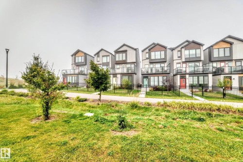 Contemporary multi-story facades with varied cladding, private balconies featuring glass railings, and individual front entrances - 479 39 St Sw, Edmonton, AB 
