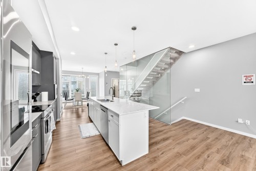 Modern kitchen featuring a central island with an undermount sink, stainless steel appliances, and sleek gray cabinetry - 479 39 St Sw, Edmonton, AB 