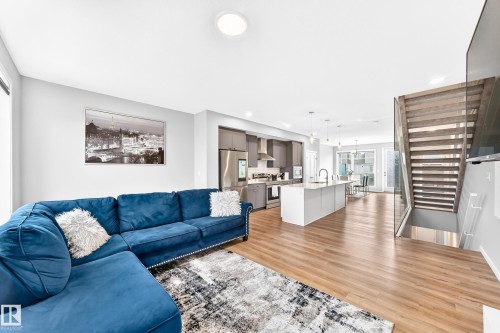 Open-concept living area with wood-finish flooring, recessed lighting, and a modern kitchen - 479 39 St Sw, Edmonton, AB 