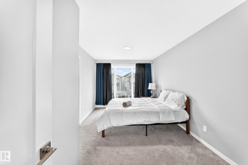 Wall-to-wall carpeting and a ceiling-mounted light fixture illuminate this room with light gray walls - 479 39 St Sw, Edmonton, AB 