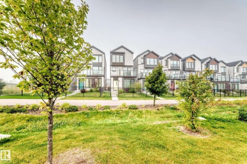Modern townhouse exteriors featuring varied rooflines, glass balcony railings, and individual front walkways - 479 39 St Sw, Edmonton, AB 