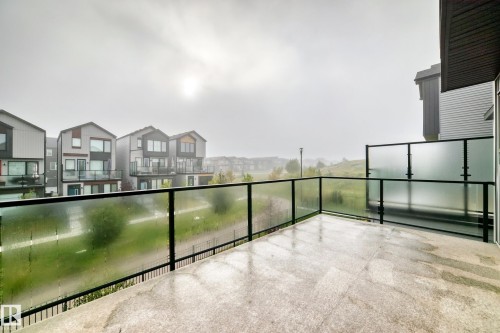 Spacious outdoor balcony with concrete flooring, clear glass railing, and frosted privacy glass panels - 479 39 St Sw, Edmonton, AB 