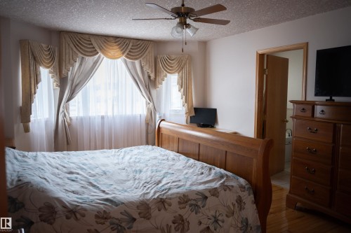 Bay window with decorative valances and sheer curtains, ceiling fan with integrated lighting, and wood-finish flooring - 16503 68 Street Nw, Edmonton, AB 