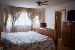 Bay window with decorative valances and sheer curtains, ceiling fan with integrated lighting, and wood-finish flooring - 