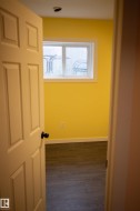 Wood-finish flooring with white baseboards, bright yellow walls, and a window with white trim - 